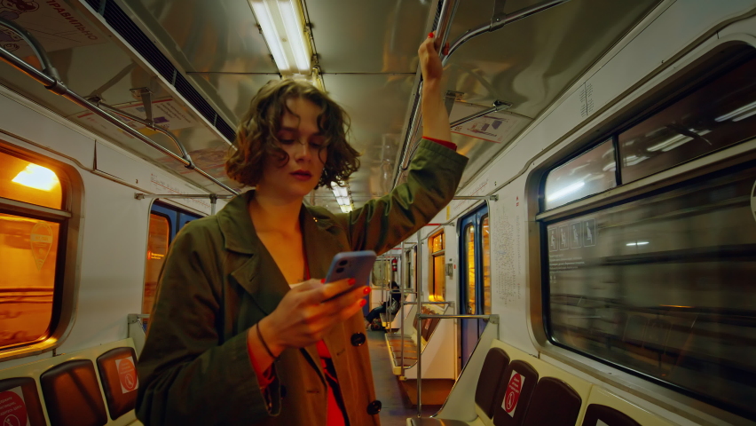 Cinematic movie shot of young woman stand in dark subway car when its on the move. Commuting in metro to work or going out party. Nightlife in big city lifestyle concept. Woman look at phone in subway Royalty-Free Stock Footage #1086936143
