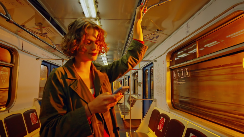 Cinematic movie shot of young woman stand in dark subway car when its on the move. Commuting in metro to work or going out party. Nightlife in big city lifestyle concept. Woman look at phone in subway | Shutterstock HD Video #1086936143