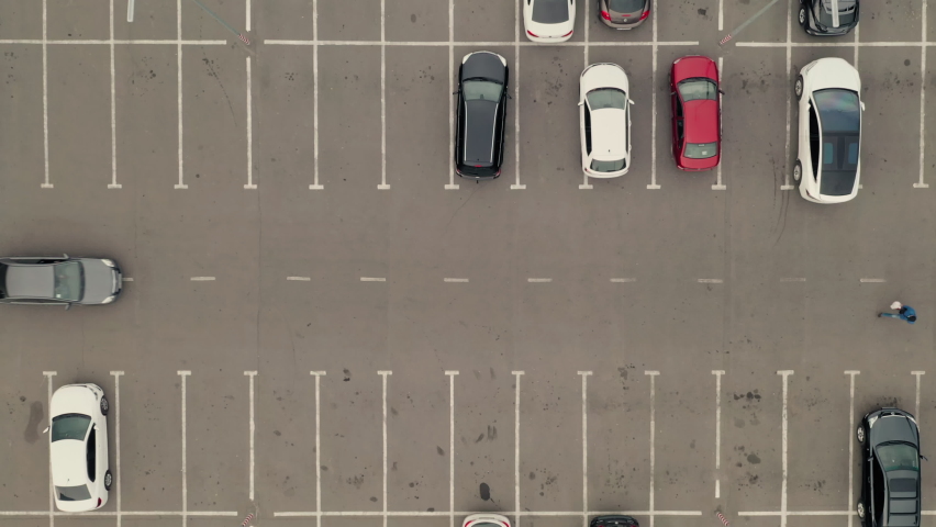 Cars arrive at the parking lot and park in free spaces. Car pass throw the parking lot. Car leaves the parking lot - aerial top overhead drone shot. | Shutterstock HD Video #1086940472