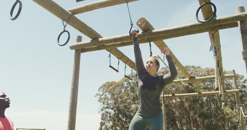 Fit caucasian woman falling from bars at obstacle course helped by african american male colleague. healthy active lifestyle, cross training outdoors at boot camp.