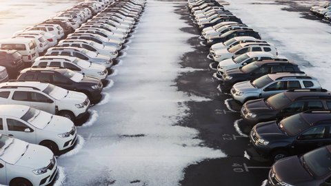Aerial low angle view of the car park of a car dealership or customs terminal with rows of new SUVs (crossovers) and cars