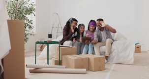 Video call tablet, married couple and their children call family via internet to show renovated apartment, everyone waves hello with smile, man spins around with device woman explains progress