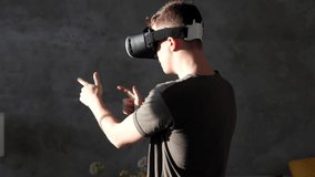 Man plays with virtual reality glasses on a sunny day. Man touching something with modern 3d vr glasses indoors.