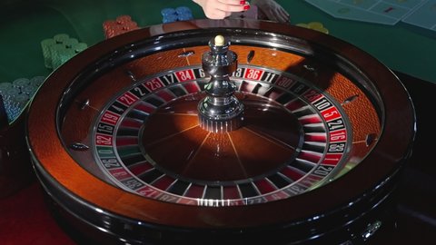 Close up shot of a spinning roulette. luxury casino roulette wheel. Female hands with red manicure spinning the ball on elegant roulette with golden and leather elements. Gambling. Lucky game.