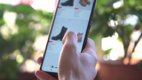 A Man at Home Using Smartphone Buys in Internet Shop. Customer Orders shoes In An Online Store Using a Smartphone. Online Shopping