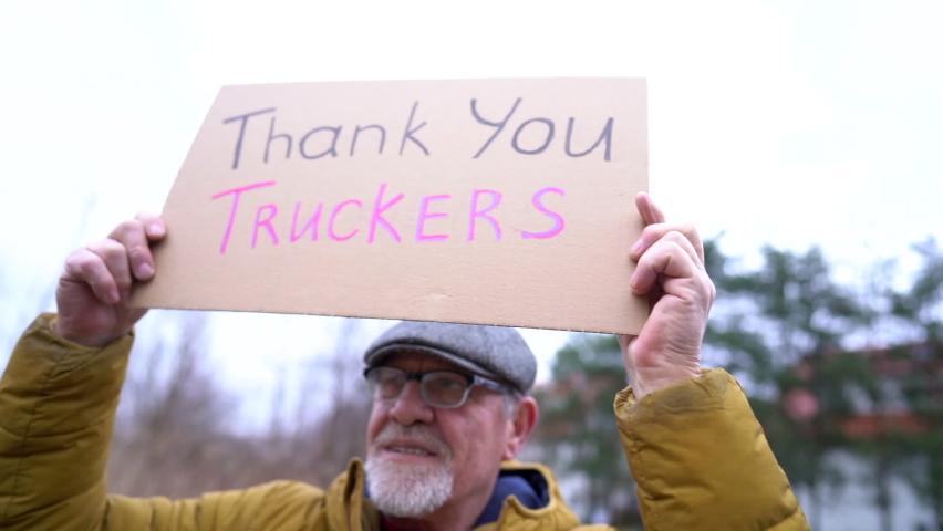Poster with the inscription Thank you truckers in the hands of an elderly man in winter clothes and a cap. Strike in support of the movement Freedom convoy 2022 in Canada Royalty-Free Stock Footage #1086951995