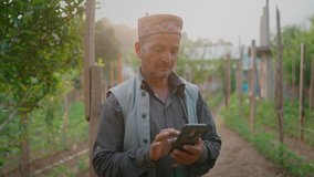 A middle aged Indian Asian rural man or male farmer in traditional costumes is using an agricultural app on a mobile phone standing on a farm in the countryside. Concept of technology in agriculture - Powered by Shutterstock - Get 15% off with code: PIKWIZARD15