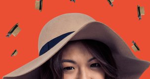 Animation of asian woman with hat over falling hats on red background. fashion design and clothing concept digitally generated video.