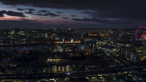 Establishing Aerial View Shot of London UK, United Kingdom, Palace of Westminster, British Parliament, at nigh evening, tack in, trains pass by