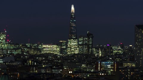 Establishing Aerial View Shot of London UK, United Kingdom, City of London and skyscrapers, at night evening, flying low and slow