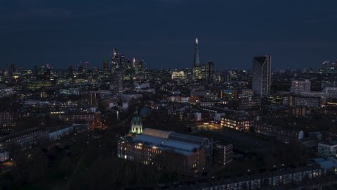 Establishing Aerial View Shot of London UK, United Kingdom, City of London and skyscrapers, at night evening, push over Imperial War Museum