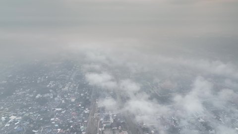flying above Phra Prathom Chedi city with mist slowly form over the cloud to town 4k stock footage low contrast