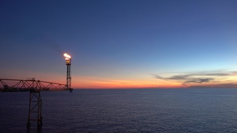 flare burning bridge of oil and gas platform or offshore platform with sun rise and beautiful clouds in the sea for oil and gas industry concept.