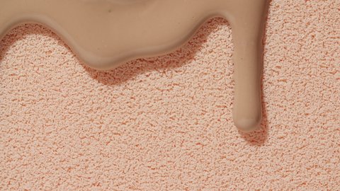 Foundation for face, smear, concealer, cosmetic liquid foundation, or cream beige color smudge flowing down on sponge. Beauty skincare sample. Macro Shot. Close up