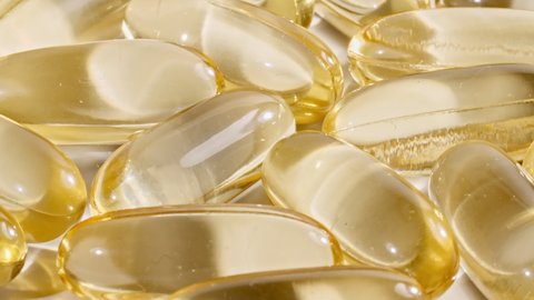 Yellow capsules medical pills rotating closeup. Vitamin C, Omega 3 in oil capsules. Pills and drugs. Pharmaceutical Industry. The medicine concept. Slow motion