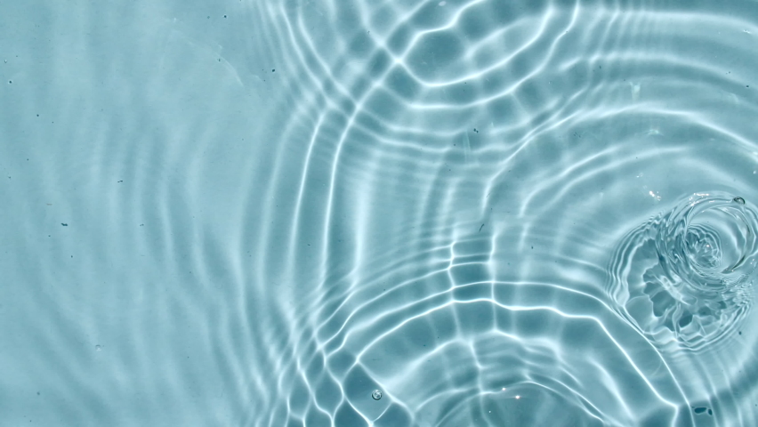 Top view slow motion of drop falls into water and diverging circles of water on blue background. Sun and shadows. Water drop splash blue colored. 4k | Shutterstock HD Video #1086961895