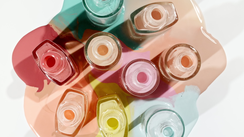 Multicolored nail polish samples spilled on white background isolated. Opened bottles nail varnish, pattern. Fashion, style. Cosmetic products.Top view. Stop motion Royalty-Free Stock Footage #1086961904