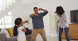 Animation of social media icons and text over parents and daughter dancing at home. global connections, digital interface and communication concept digitally generated video.