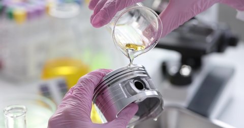 Chemist pouring engine oil on car piston in laboratory closeup 4k movie
