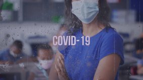 Animation of covid 19 text over female teacher in face mask in classroom. global covid 19 pandemic, education concept digitally generated video. - Powered by Shutterstock - Get 15% off with code: PIKWIZARD15