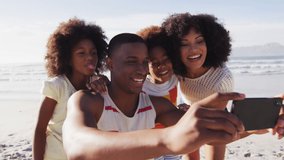 Animation of media icons over happy african american family taking selfie at beach. social media and communication interface concept digitally generated video.