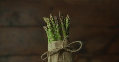 bunch of fresh asparagus tied with a rope in a bow with raindrops falling all over