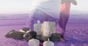 Animation of senior african american couple practicing yoga at beach over candles. leisure and wellbeing concept digitally generated video.