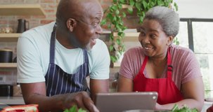 Animation of happy african american couple using tablet over lightbulbs. family spending time at home concept digitally generated video.