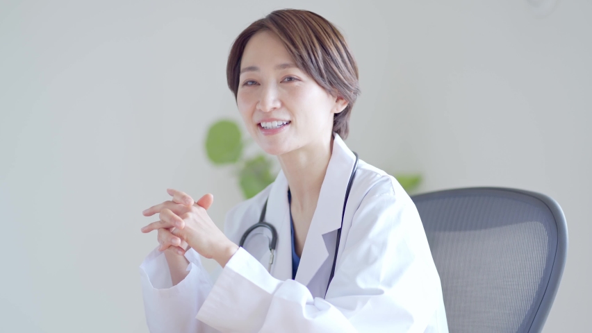 Japanese woman in a lab coat talking at the hospital | Shutterstock HD Video #1086972161