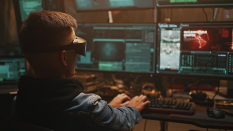 A hacker in a virtual reality headset uses a computer with on-screen interfaces to hack into the government's nuclear weapons launch control system. Underground hacker base.