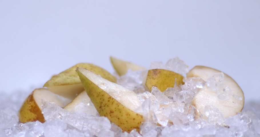 Slow motion of ice cubs filling in sliced pears, fresh fruits for juicy, cold, white food for summer time. Filmed on high speed cinema camera, 8K downscale, 4K.