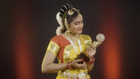 Excited bharatanatyam dancer receiving winner trophy in dancing compitation by asying thank you - concept of successful, achievement, proud and indian traditional culture.