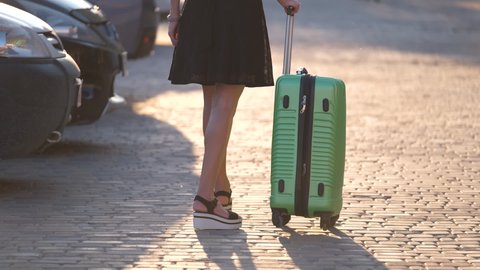 Young female driver loading luggage suitcase bag inside her car. Travelling and vacations concept