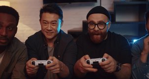 Portrait of Men Friends sitting at Home playing Video Games and Cheering. Happy Group of Diverse Men using PlayStation looking at TV sitting on couch