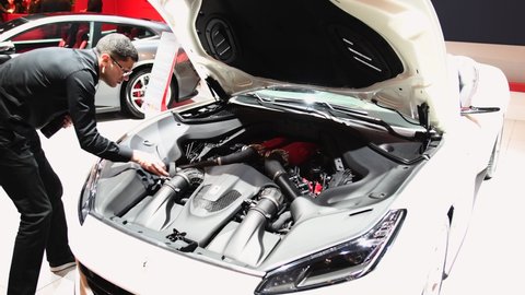 Brussels, Belgium - January 10, 2018: Man cleaning the V8 engine of a Ferrari Portofino grand touring two-door 2+2 convertible sports car on display at the 2018 European motor show in Brussels.