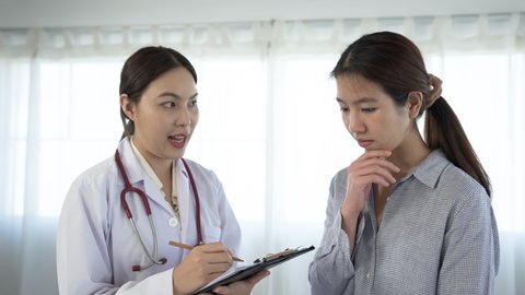 An Asian female doctor is explaining the symptoms of a 2-month-old newborn to her mother to find a cure. in the examination room of the hospital