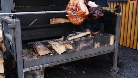 A spit for cooking roast shank in Prague. A big piece of meat. The street food.