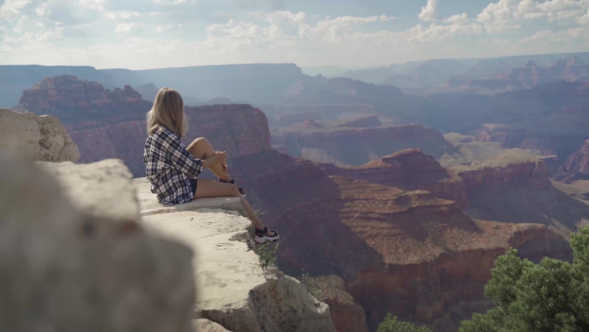 A young woman looking to Horseshoe Bend and Colorado river from the edge of 1000ft canyon in Glen Canyon National Recreation Area, Arizona, USA