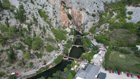 Aerial drone view of Vrelo Bune city under mountain, historical ottoman dervish lodge built under the rock and on the bank of the Buna river in Bosnia and Herzegovina
