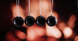 Balls in Newton's pendulum hit the background of fire. Slow-motion video