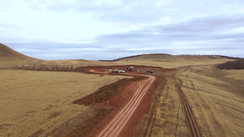 Oil field development. A drilling rig among the hills on a cloudy autumn day.
