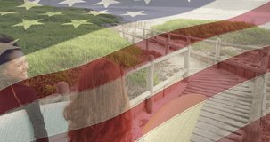 Animation of flag of united states of america over happy man and woman with surfboards on beach. american history, patriotism and independence concept digitally generated video.