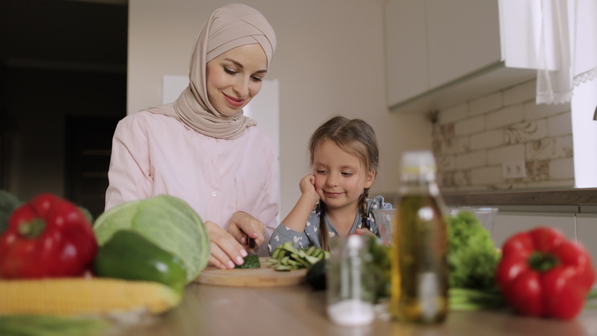 Arabian mother teach little preschooler daughter chop vegetables preparing salad for lunch together, loving mom and small girl child cooking dinner together, kid helping mommy with food preparation Royalty-Free Stock Footage #1086996503