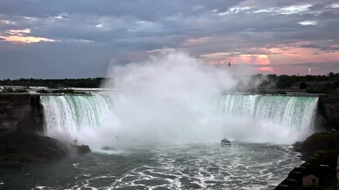 NIAGARA FALLS, CANADA - MAY 28, 2016: Sunset over Niagara Falls from Canadian side with tourist boat under Niagara waterfall.This is very popular destination in Canada near border with US.