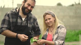 Front view video of cheerful couple smiling to camera and holding a green bean collected fresh from garden