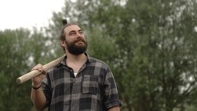 Slow motion video of bearded man holding his hoe on his shoulder and looking up