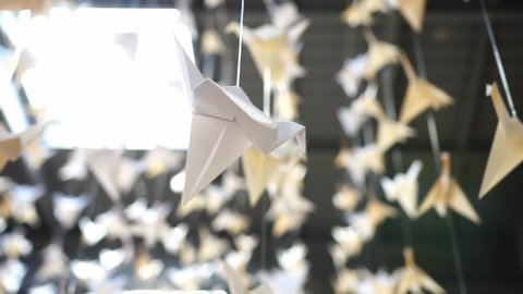 Paper cranes hanging from a ceiling with a skylight