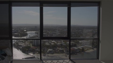 A timelapse of a setting sun leaking a warm glow onto the Gold Coast City buildings as well as a buistling river below from the view of a high apartment building with large welcoming windows