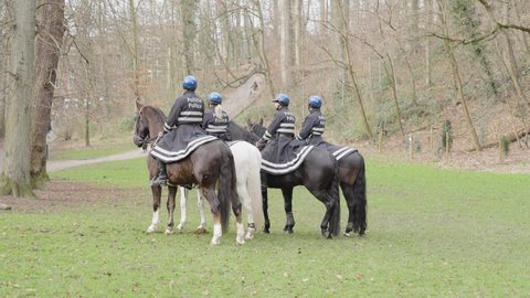 Vorst , Belgium - 01 30 2022: Four police officers mounted on horseback standing still in the park - Dudenpark