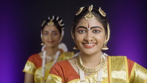 Rack focus shot of smiling Bharatnatyam dancers on stage performance - concept of Indian classcal dancers, entertainment and traditional culture
